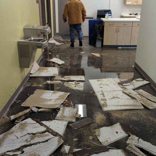 Commercial office hallway with standing water and collapsed ceiling tiles