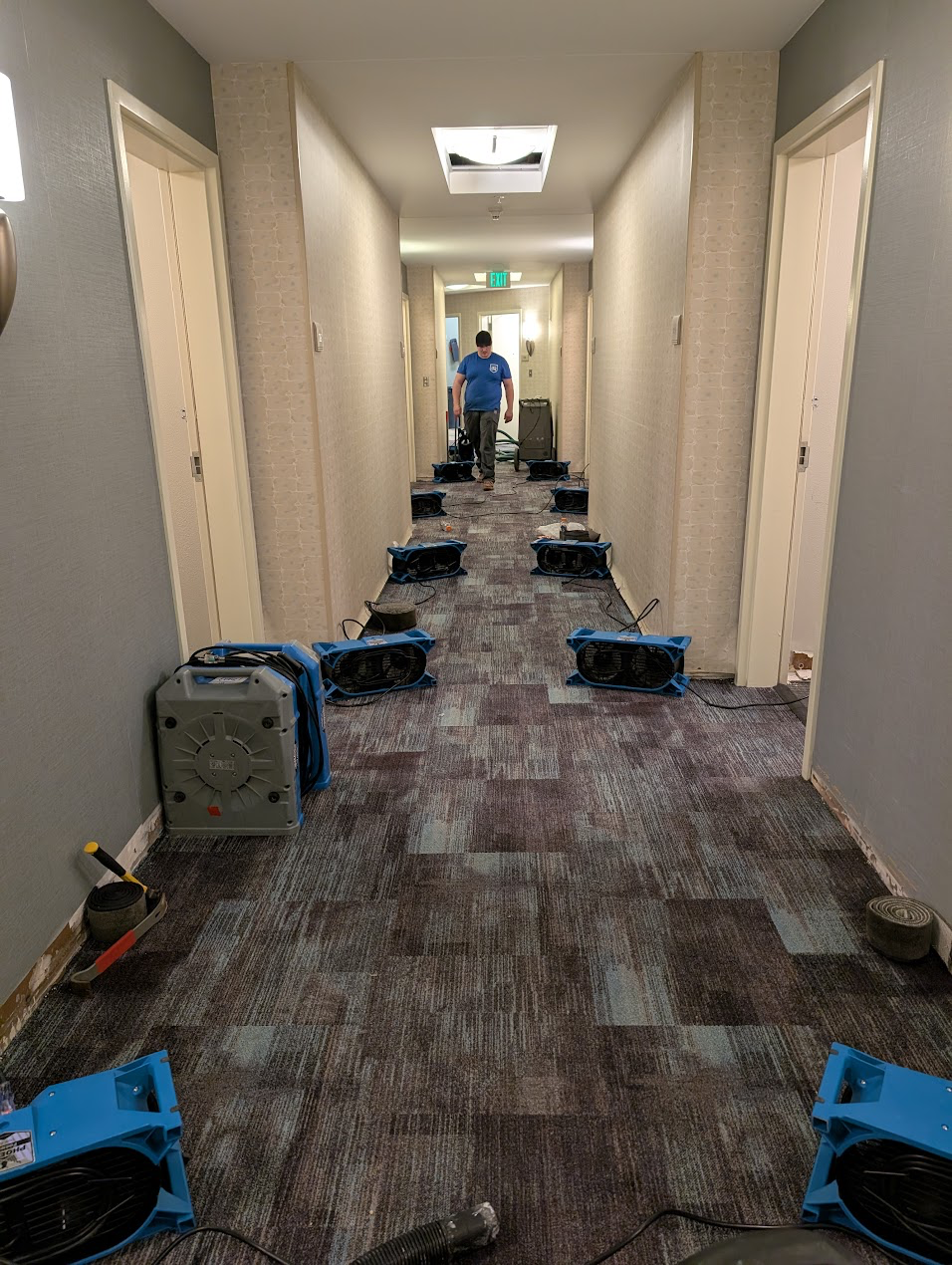 Rows of air movers along a commercial hotel hallway during water damage drying